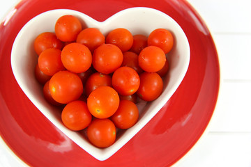 Cherry tomatoes in a heart shaped bowl on red plate