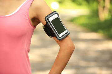 woman runner listening to music in headphones from smart phone m