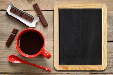 Coffee cup with chocolate and blackboard on wooden background