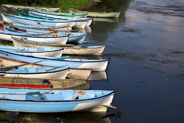 Fototapeta na wymiar Group of fishing boats aligned near lake