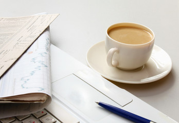 Cup of coffee near the laptop and newspapers