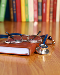 Stethoscope on book with leather cover and glasses