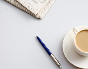 Cup of coffee near newspapers, pen