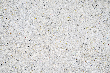 White cement wall with tiny rock on surface, grunge background.