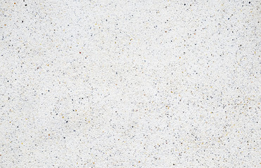 White cement wall with tiny rock on surface, grunge background.