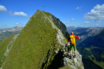 Bergsteiger mit Balance auf extrem schmalem Grat vor Berggipfel