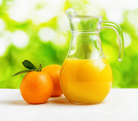 Jug of orange juice on nature background