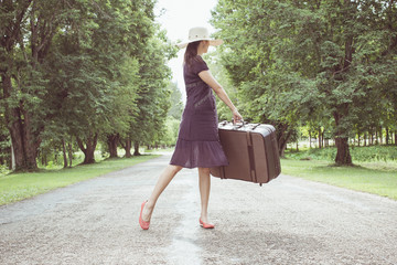 woman with retro vintage luggage on empty street