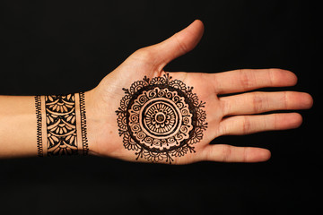 hand with mehendi on black background