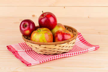 Fresh red apples in basket on wood.