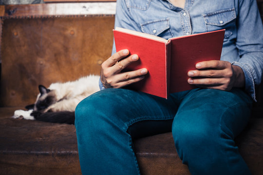 man reading on sofa with cat