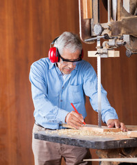 Senior Carpenter Cutting Wood With Bandsaw