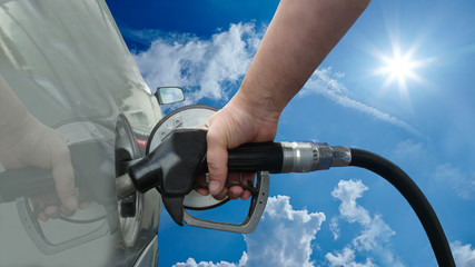 ccc18 CarCleaningConcept - german: Auto wird mit Kraftstoff betankt / Sonne / Wolken - english: vehicle with diesel gas fuel / holding a fuel nozzle / sun / clouds - 16to9 - g1754
