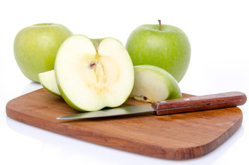 Ripe green apples with slices on a wooden cutting board