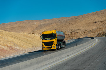 Fototapeta premium Yellow truck on the road in the desert landscape