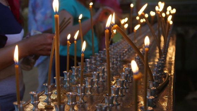 Faithful people lighting prayer candles in the church c