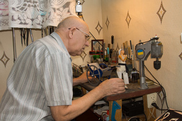 Elderly man building a model of a girl and cart