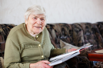 Old beautiful senior woman of 85 years reading book, indoors