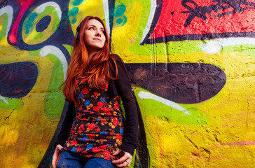 young redhead woman at colorful graffiti wall