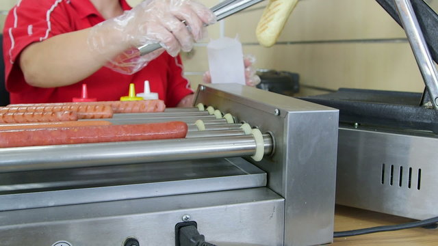 Employee making top loader hot dog in fast food takeout dinner