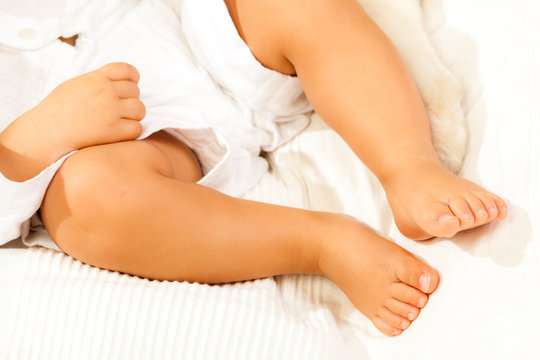 Gambe di un neonato sdraiato su un lenzuolo bianco