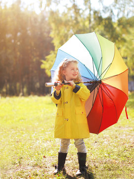 Positive child with colorful umbrella in autumn day