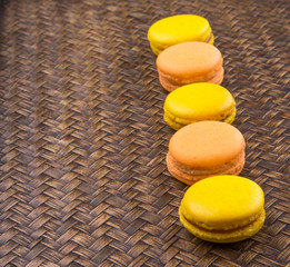 Yellow and orange colored French macarons on wicker background