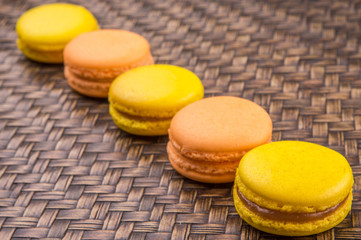 Yellow and orange colored French macarons on wicker background