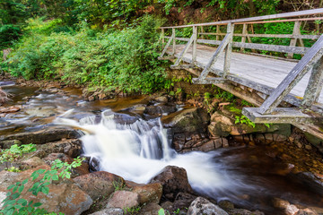 Mountain stream flowing under a wooden bridge