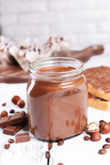 Sweet chocolate cream in jar on table on light background