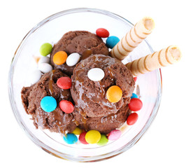 Chocolate ice cream with multicolor candies and wafer rolls in