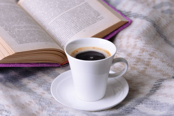 Cup of coffee on plaid with book