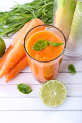 Glass of fresh carrot juice, spring onion, lime, tuft of grass
