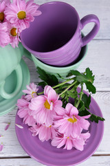 Fototapeta na wymiar Cups and saucers with flowers on wooden background