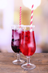 Glasses of cold berry cocktail on wooden table