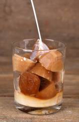Iced coffee cubes with cold milk in glass on wooden background
