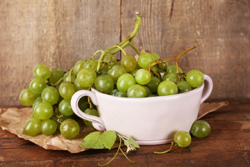 Green grapes in bowl on wooden background