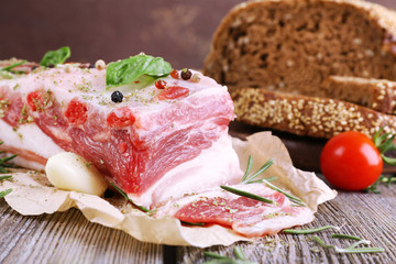 raw bacon with bread and spices on wooden table