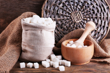 Refined sugar in bag and bowl on wooden background