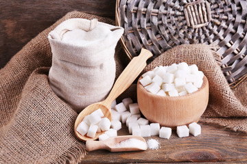 Refined sugar in bag and bowl on wooden background