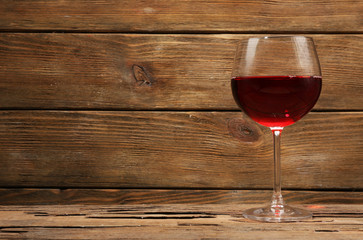 Glass of red wine on wooden table on wooden wall background