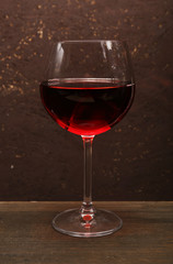 Glass of red wine on wooden table on wooden wall background