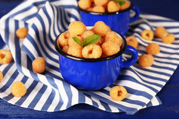 Yellow raspberries in dark blue mugs