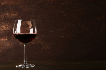 Goblet of red wine on wooden table on wooden wall background