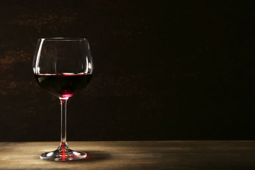 Goblet of red wine on wooden table on wooden wall background