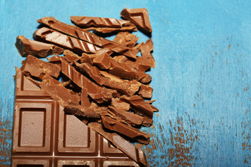 Milk chocolate bar on color wooden background