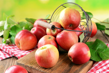 Sweet apples in wicker basket on table on bright background
