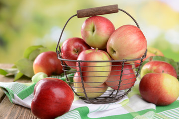 Sweet apples in wicker basket on table on bright background