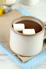 Hot chocolate with marshmallows in mug, on wooden background