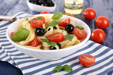 Spaghetti with tomatoes, olives and basil leaves